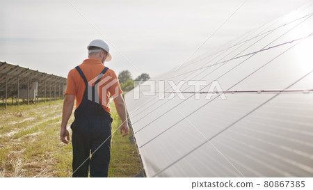 Assistance technical worker in uniform is checking an operation and efficiency performance of photovoltaic solar panels. Concept of electricity, ecology. Farm of solar panels. Green energy 80867385