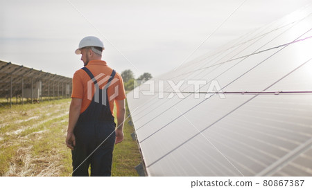 Assistance technical worker in uniform is checking an operation and efficiency performance of photovoltaic solar panels. Concept of electricity, ecology. Farm of solar panels. Green energy Assistance technical worker in uniform is checking an operation and efficiency performance of photovoltaic solar panels. Concept of electricity, ecology. Farm of solar panels. Green energy 80867387