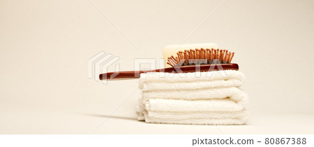 Hairbrush and towels at light background. Minimalistic wellness concept Hairbrush and towels at light background. Minimalistic wellness concept 80867388
