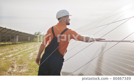 Assistance technical worker in uniform is checking an operation and efficiency performance of photovoltaic solar panels. Concept of electricity, ecology. Farm of solar panels. Green energy Assistance technical worker in uniform is checking an operation and efficiency performance of photovoltaic solar panels. Concept of electricity, ecology. Farm of solar panels. Green energy 80867389