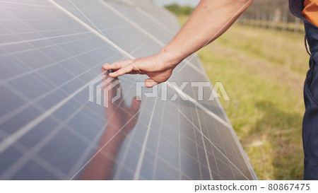 Close up of a young engineer hand is checking the operation of sun and cleanliness of photovoltaic solar panels on a sunset. Close-up of modern photovoltaic solar battery. 80867475