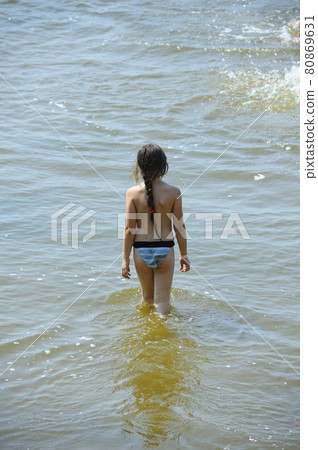 Little girl going in water of river to swim 80869631