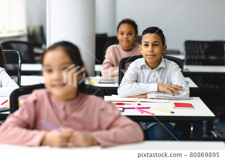 Portrait of small boy sitting at desk in classroom Portrait of small boy sitting at desk in classroom 80869895