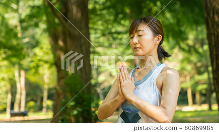 A woman doing yoga and refreshing in a natural park 80869985