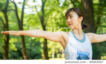 A woman doing yoga and refreshing in a natural park 80869987