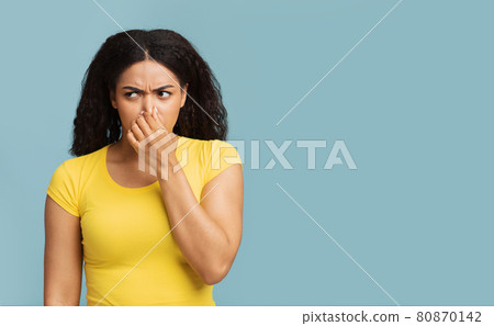 African american woman closing nose with fingers, feeling unpleasant scent, standing over blue background, free space African american woman closing nose with fingers, feeling unpleasant scent, standing over blue background, free space 80870142