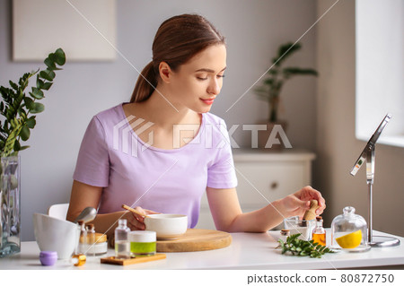A woman in a room, preparing natural purple blush cosmetic. A woman in a room, preparing natural purple blush cosmetic. 80872750