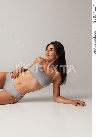 Cropped image of young adorable woman in lingerie isolated over gray studio background. Natural beauty concept. Cropped image of young adorable woman in lingerie isolated over gray studio background. Natural beauty concept. 80874114