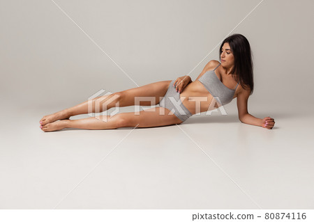 Young adorable woman in lingerie isolated over gray studio background. Natural beauty concept. Young adorable woman in lingerie isolated over gray studio background. Natural beauty concept. 80874116