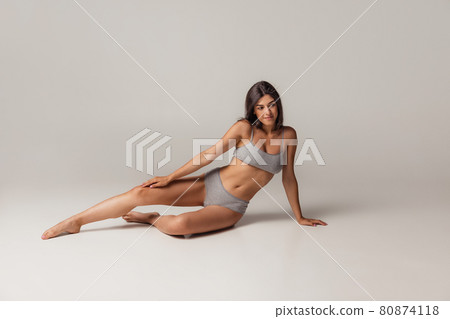 Young adorable woman in lingerie isolated over gray studio background. Natural beauty concept. Young adorable woman in lingerie isolated over gray studio background. Natural beauty concept. 80874118