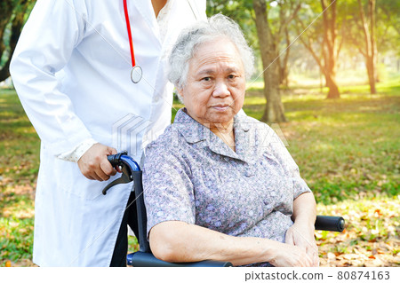 Doctor help and care Asian senior or elderly old lady woman patient sitting on wheelchair at park in nursing hospital ward : healthy strong medical concept . Doctor help and care Asian senior or elderly old lady woman patient sitting on wheelchair at park in nursing hospital ward : healthy strong medical concept . 80874163