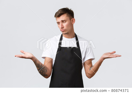 Cafe and restaurants, coffee shop owners and retail concept. Disappointed gloomy waiter, salesman in black apron sighing upset, showing two variants on palms and looking sad at left hand 80874371