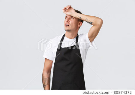 Employees, grocery stores and coffee shop concept. Tired waiter looking up and exhaling from fatigue, barista wipe sweat from forehead need break, feeling exhausted serving tables, white background Employees, grocery stores and coffee shop concept. Tired waiter looking up and exhaling from fatigue, barista wipe sweat from forehead need break, feeling exhausted serving tables, white background 80874372