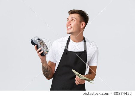 Small retail business, payments and employees concept. Friendly handsome waiter, serving tables, barista giving customer POS terminal and money, looking left, white background 80874433