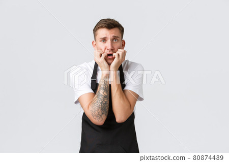 Employees, grocery stores and coffee shop concept. Scared insecure barista, guy waiter feel anxious and frightened, biting fingernails and shaking from fear, standing white background 80874489