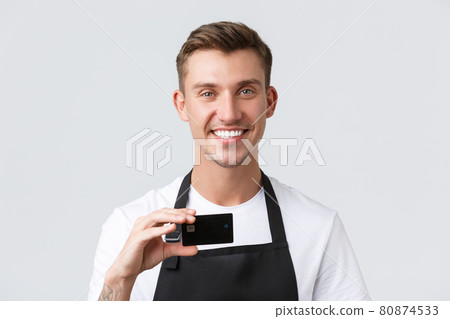 Cafe and restaurants, coffee shop owners and retail concept. Close-up of handsome friendly-looking waiter, salesman smiling broadly and showing credit card, contactless payment option 80874533