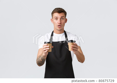 Small business, coffee shop, cafe and restaurants concept. Handsome barista, waiter giving out takeaway coffee in paper cups, prepared order for guests, selling drinks over white background 80875729