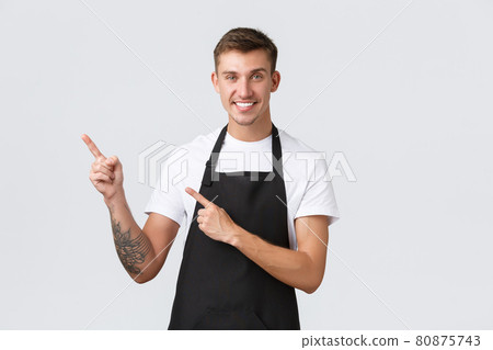 Small business owners, coffee shop and staff concept. Handsome friendly barista, guy in black apron pointing fingers left and smiling, inviting enjoy drink in cafe, white background Small business owners, coffee shop and staff concept. Handsome friendly barista, guy in black apron pointing fingers left and smiling, inviting enjoy drink in cafe, white background 80875743