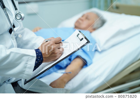 Doctor writing down the diagnosis on clipboard while Asian senior or elderly old lady woman  lying on bed in nursing hospital ward : healthy strong medical concept.. 80875820