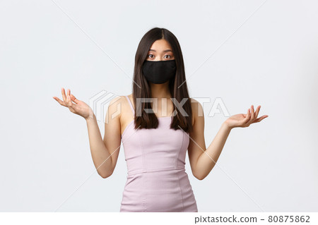 Covid-19, social distancing quarantine and leisure concept. Confused asian woman in evening party dress and face mask, cant understand what happened, shrugging with hands sideways, look puzzled 80875862