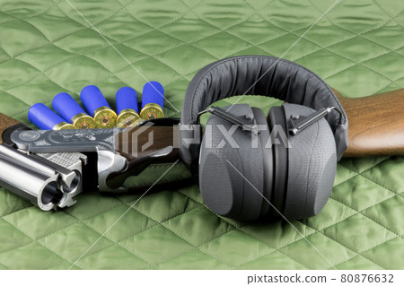 Shotgun with Cartridges and Hearing Protection on a Country Coat 80876632