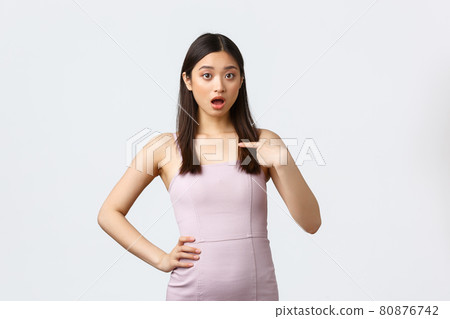 Luxury women, party and holidays concept. Surprised and astonished asian woman in evening dress, open mouth gasping as pointing finger at herself, being mentioned or chosen, white background Luxury women, party and holidays concept. Surprised and astonished asian woman in evening dress, open mouth gasping as pointing finger at herself, being mentioned or chosen, white background 80876742