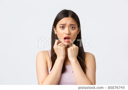 Beauty, fashion and people emotions concept. Close-up portrait of concerned and scared, timid asian girl, hold hands pressed to chest, gasping afraid, looking worried, white background Beauty, fashion and people emotions concept. Close-up portrait of concerned and scared, timid asian girl, hold hands pressed to chest, gasping afraid, looking worried, white background 80876745