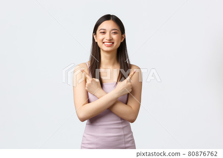 Luxury women, party and holidays concept. Smiling happy and cute asian girl in evening dress, pointing fingers sideways, showing left and right promo choices, give advice, recommending Luxury women, party and holidays concept. Smiling happy and cute asian girl in evening dress, pointing fingers sideways, showing left and right promo choices, give advice, recommending 80876762