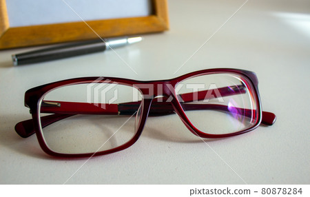 Beautiful glasses, metal pen and frame on a white table. Business concept. 80878284
