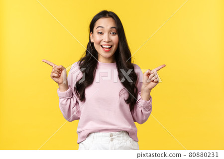 People emotions, lifestyle and fashion concept. Excited young 20s asian woman pointing fingers sideways, showing left and right advertisement, smiling broadly, expressing joy and thrill 80880231
