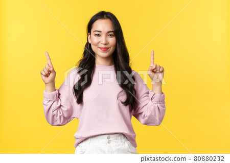 People emotions, lifestyle and fashion concept. Pleasant smiling attractive woman in stylish clothes pointing fingers up, demonstrate product link, advertising over yellow background People emotions, lifestyle and fashion concept. Pleasant smiling attractive woman in stylish clothes pointing fingers up, demonstrate product link, advertising over yellow background 80880232