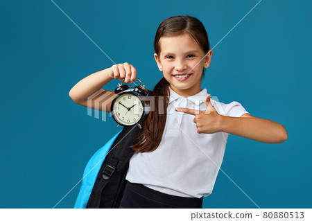schoolgirl with backpack is holding alarm clock 80880513