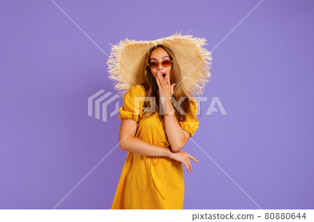 elegant woman in a light dress with a straw hat on her head holds the other on her neck 80880644