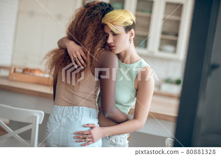 Woman with dyed hair hugging dark-skinned girlfriend Woman with dyed hair hugging dark-skinned girlfriend 80881328