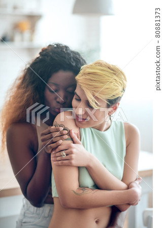 African american woman hugging standing behind her girlfriend African american woman hugging standing behind her girlfriend 80881373