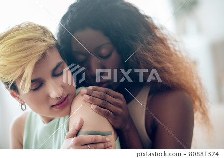 Woman with closed eyes and girlfriend touching back 80881374