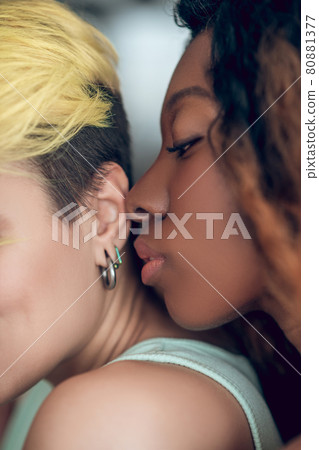 Dark-skinned woman mouth approaching her girlfriend ear Dark-skinned woman mouth approaching her girlfriend ear 80881377