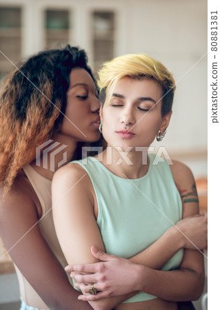 Dark-skinned woman standing behind her girlfriend back Dark-skinned woman standing behind her girlfriend back 80881381