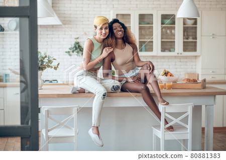 Two girlfriends in kitchen in cheerful mood Two girlfriends in kitchen in cheerful mood 80881383