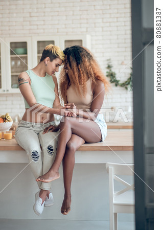 Two women touching their heads sitting on table Two women touching their heads sitting on table 80881387