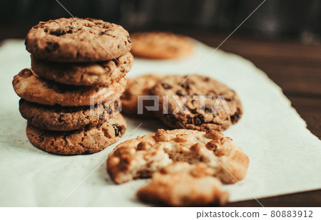 Chocolate cookies on parchment paper. Broken biscuits on a wooden table. Selective focus. Chocolate cookies on parchment paper. Broken biscuits on a wooden table. Selective focus. 80883912