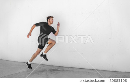 Sport athlete training running fast with explosive sprint for competition. Man runner working out at fitness gym outdoor white wall background. 80885108