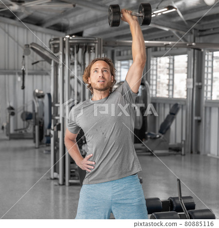 Gym workout fitness man training with dumbbells lifting overhead raise shoulders exercise shoulder press indoors at health club. Square crop. 80885116