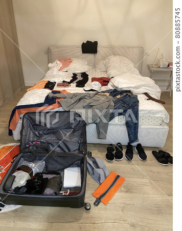 Open Suitcase lay on floor with mess on bed and around room. Packing or unpacking luggage. Open Suitcase lay on floor with mess on bed and around room. Packing or unpacking luggage. 80885745