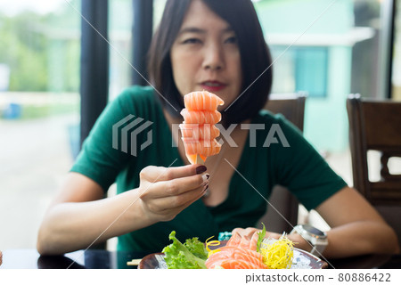 Hands woman holding fresh salmon sashimi in restaurant Hands woman holding fresh salmon sashimi in restaurant 80886422
