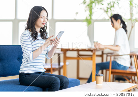 一名年輕女子在共享辦公空間操作智能手機。 80887012