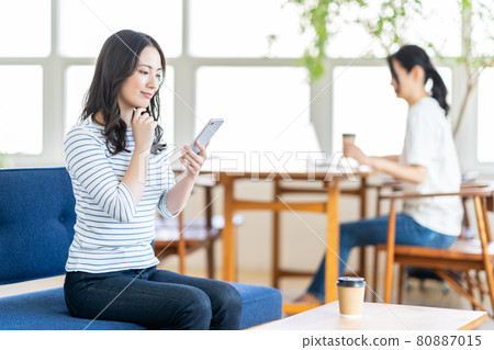 一名年輕女子在共享辦公空間操作智能手機。 一名年輕女子在共享辦公空間操作智能手機。 80887015