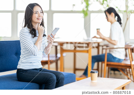一名年輕女子在共享辦公空間操作智能手機。 80887018