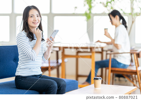 一名年輕女子在共享辦公空間操作智能手機。 一名年輕女子在共享辦公空間操作智能手機。 80887021