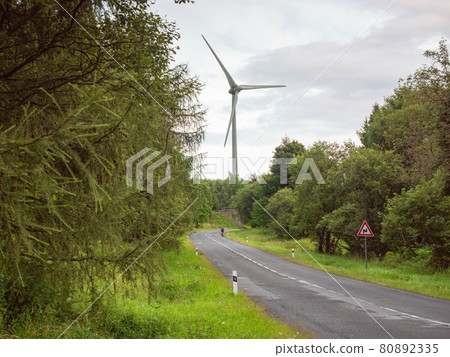 Wind turbines on the peaks above Asphalt road between tree Wind turbines on the peaks above Asphalt road between tree 80892335